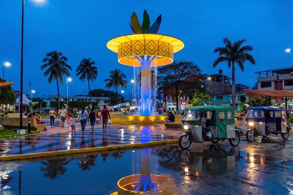 Plaza de Armas de Satipo al anochecer, con su torre amarilla iluminada y mototaxis esperando pasajeros